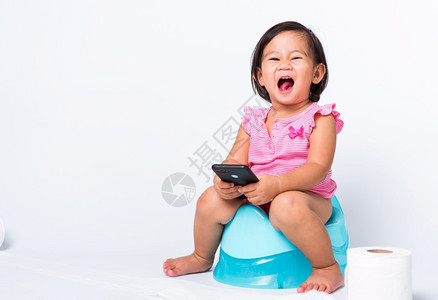 亚洲可爱的小婴儿女教育培训他们坐在蓝室锅或便壶上用卫生纸卷玩智能手机在白色背景上单独拍摄工作室Wc厕所图片