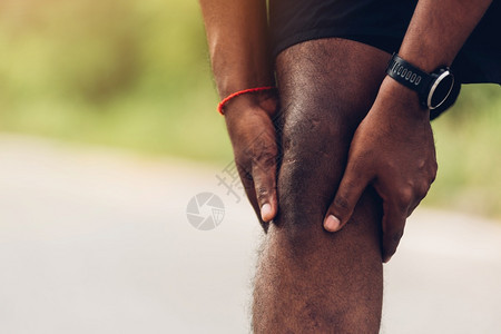 在户外街头健康公园跑动时黑人男子穿着手表用握紧膝盖疼痛身体运动因锻炼概念受伤图片