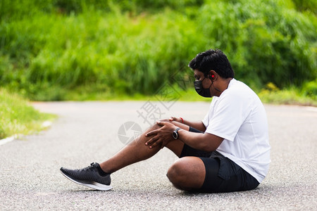 黑人在户外街头健康公园跑时用手握住膝盖图片