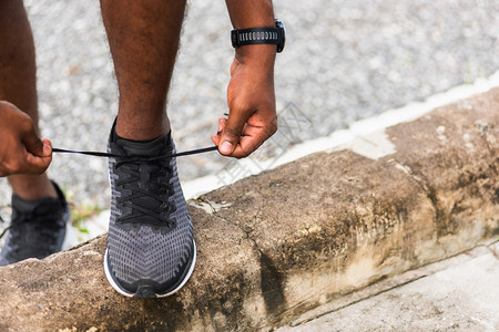 近亚洲运动赛跑的黑人在徒步路上站着手表尝试鞋带跑准备步和户外街头健康公园锻炼概念图片