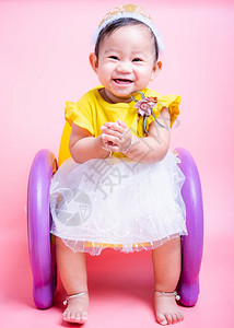 坐在椅子上她是一个在工作室里微笑的容以粉红背景与世隔绝Baby9个月图片