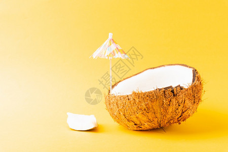 快乐椰子日概念新鲜椰子和太阳伞黄背景孤立的摄影棚沙滩热带水果春季暑假图片