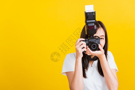 亚洲美丽年轻女摄影师笑容的喜悦拍摄照片并透过古老的数码无镜照摄影机拍影棚图片