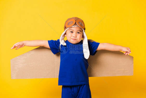 男孩戴着飞行员帽子玩着纸板飞机图片