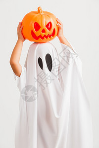 有趣的万圣儿基概念可爱的小孩穿着白色服装扮圣礼幽灵吓坏了他手握着橙南瓜鬼图片