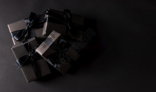 黑色星期五销售购物概念黑纸和弓丝带包裹的礼品盒最佳视野黑背景摄影棚拍图片