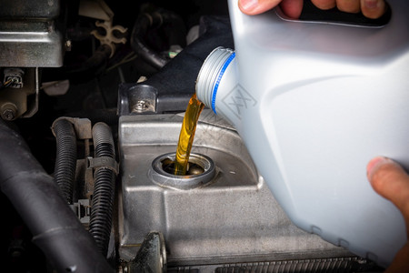 在维修服务站理汽车加油和从瓶倒灌换润滑油的机械能源燃料汽车概念图片