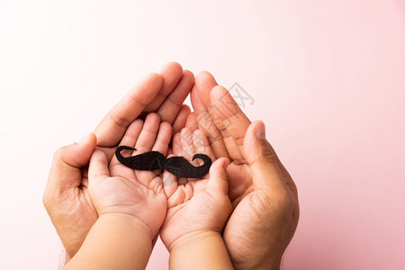 父亲和儿子的用手握着黑胡摄影棚拍在白色背景上被孤立前列腺癌症意识月父亲日1月最小的胡子概念图片