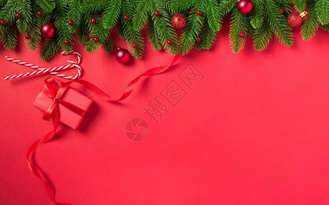 圣诞假日背景配有礼品盒装饰红桌背景上Fir绿色fir树枝和Xma装饰品图片