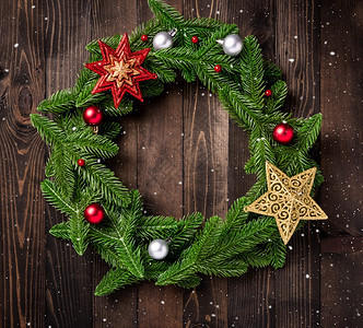 带有装饰品的圣诞花圈树壁枝的顶部视图滚动在一个圆圈中黑桌木本底的装饰明星中滚动新年节庆装饰概念图片