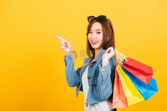 亚洲快乐的肖像美丽可爱的年轻少女带着太阳镜微笑的少女站在太阳镜面前兴奋地拿着购物袋图片