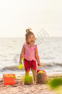 快乐的亚洲儿童可爱的小女孩玩沙子具工在热带海滨图片
