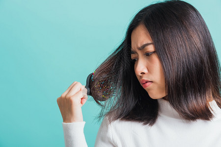 年轻的亚洲美女对梳子和问题头发心烦意乱图片