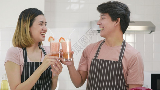 快乐的亚洲美丽年轻夫妇妻享受喝新鲜苹果冰淇淋在厨房里喝新鲜苹果冰淇淋在早上一起用玻璃在家中健康的生活方式概念图片