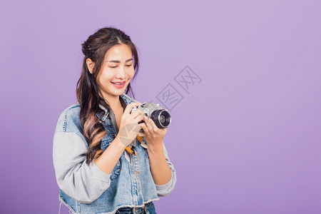 带着古老的摄影机年轻女旅行者摄影师棚拍下紫色背景的孤立镜头图片
