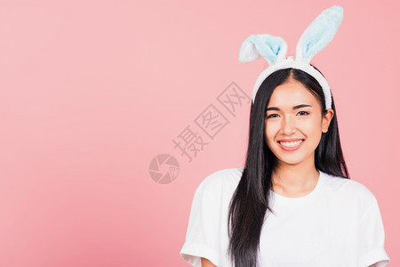 复活节快乐美丽的年轻女士微笑着兔子耳朵肖像女快乐的脸站着看摄影机棚拍孤立在粉红色背景上图片