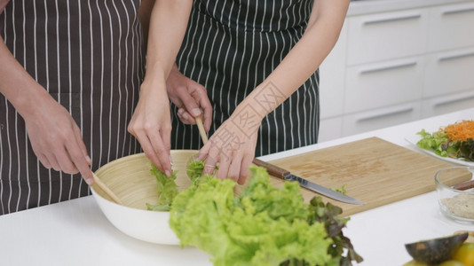 亚洲美丽家庭快乐的一对夫妇妻在家里厨房一起煮菜沙拉男人把蔬菜混在一起用个女杯子煮蔬菜健康的食物概念图片