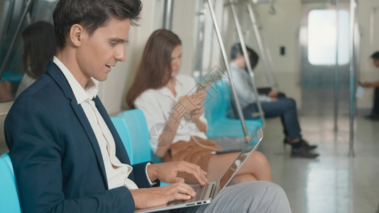 白种人青年商在上班时使用笔记本电脑在地铁火车上工作图片