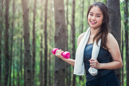 年轻女子在森林自然公园利用复制空间放松哑铃锻炼图片