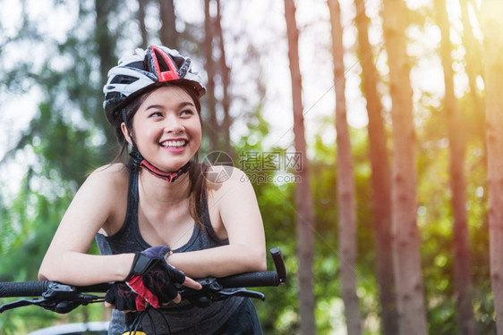 美丽的女青年带着头盔在森林里骑行图片