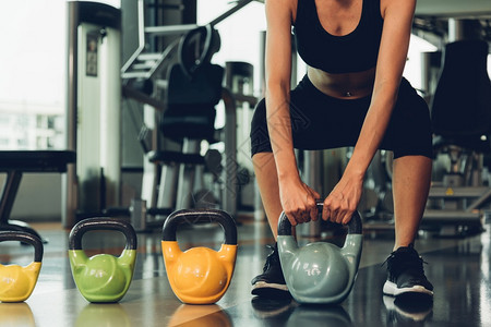 美丽的女人在健身GYM使用哑铃重量锻炼图片