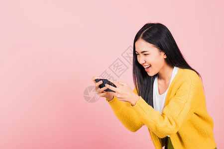 手机拍摄快乐的亚洲肖像美丽可爱的年轻少女笑着兴奋的年轻少女使用手机说是工作室拍摄孤立在粉红背景上泰国女惊讶在智能手机上做出赢家姿态背景