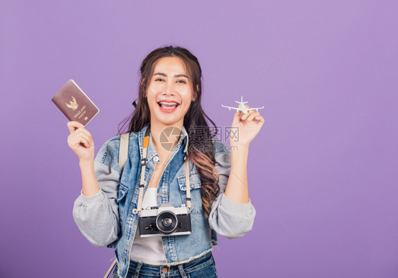 年轻女子拿着飞机玩具和护照图片