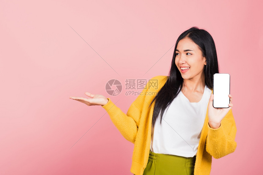 快乐的亚洲肖像美丽可爱的年轻女兴奋地握着手机空白屏幕展示产品手掌在空图片