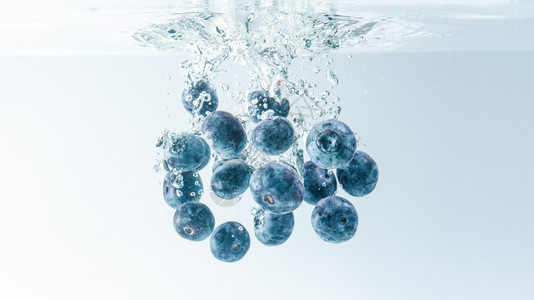 一连串美味的蓝莓漂浮在水面上沉没孤立在白色背景上喷洒食物摄影蓝莓喷洒在水面上沉没图片