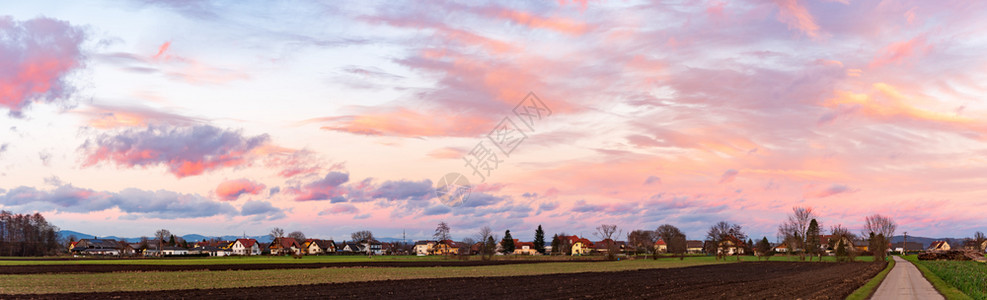 全景田野的日落和奥地利村庄天空和云彩飞扬全景是图片