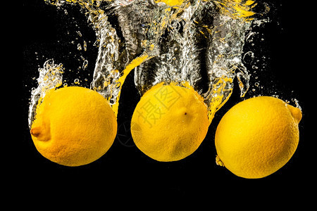 黑色背景的鲜黄柠檬加上大量的气泡清新概念黑色背景的新鲜黄柠檬图片