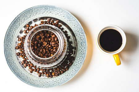 白色背景的黄陶瓷咖啡杯与豆罐子旁边的白色背景黄陶瓷咖啡杯图片