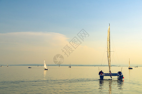 奥地利内西德列尔斯湖上的Catamaran船日落前清空平静的水与日落后空间相仿奥地利内西德列尔斯湖上的Catamaran船图片