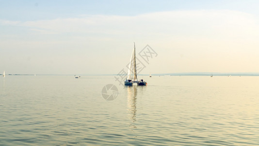 奥地利内西德列尔斯湖上的Catamaran船日落前清空平静的水与日落后空间相仿奥地利内西德列尔斯湖上的Catamaran船图片