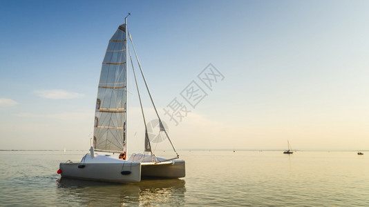 奥地利内西德列尔斯湖上的Catamaran船日落前清空平静的水与日落后空间相仿奥地利内西德列尔斯湖上的Catamaran船图片