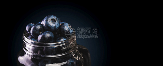 蓝莓装在玻璃罐里隔着黑色背景复制右边的空间图片