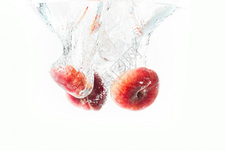 一群甜圈桃子在白色上被孤立掉入水中果与气泡一起沉入水晶清澈的中一群甜圈桃子在白色上被孤立喷入水中图片