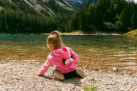 TragoessStyriaAustria1207坐在美丽的湖岸上孩子叫GreenLakeGrunerSee充满游客在湖边走动的图片