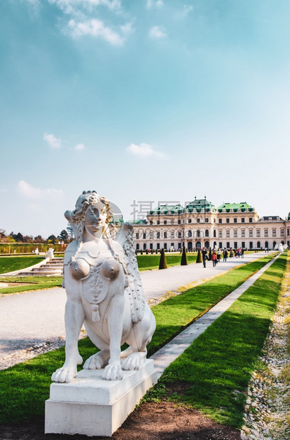 2013年4月日维也纳奥地利前景中的妇女狮身人面像背景中的贝尔韦德雷宫殿和行进中的游客图片