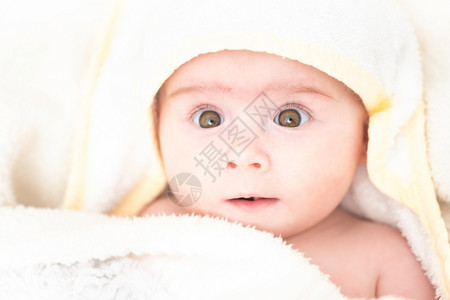洗澡后被用毛巾的可爱女婴、用棕色大眼睛向上看、复制空间洗澡的概念6个月婴儿用毛巾包着的可爱女婴、复制图片