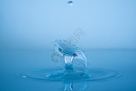 水滴落到蓝表面健康和纯洁的概念水滴涌到蓝表面图片