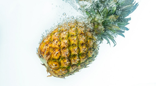 菠萝被丢入白色背景的清水中果喷洒主题图片