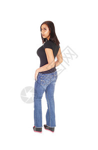 穿着牛仔裤的年轻美女站在外表的仰望着肩膀身穿黑色的顶部与白种背景隔绝图片