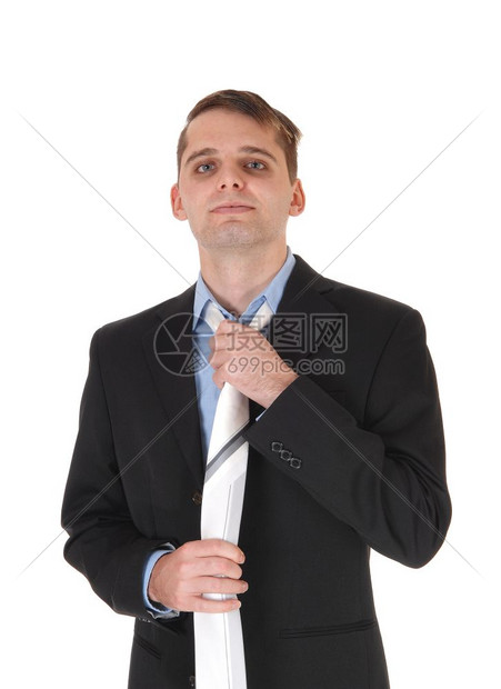 站在前面的英俊年轻男子是一个黑西装和蓝衬衫修他的领带与白背景隔离图片