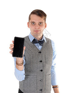 一个英俊的年轻人穿着灰色背心蓝衬衫和安眠衣拿着手机与白背景隔绝图片