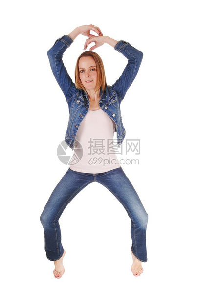 一个穿牛仔裤和外套的漂亮年轻女子赤脚站在趾上白背景隔离图片