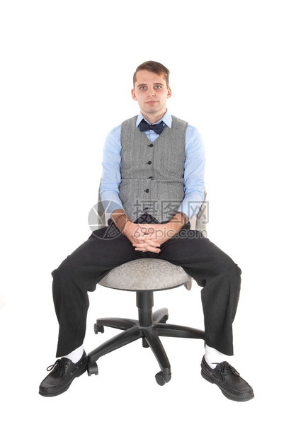 一个穿着衣服裤子的英俊年轻男穿着灰色背心蓝衬衣坐在办公室椅子上图片