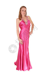 一个穿着长的粉红色晚礼服漂亮女人站在白背景的孤立处手放在臀部图片