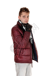 一个微笑的年轻男子站在勃冈底冬季夹克和围巾微笑孤立的白色背景图片