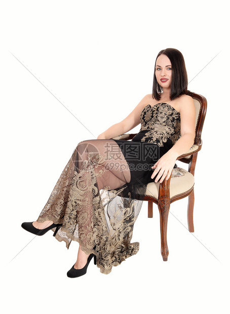 穿着黑色晚礼服的美丽年轻女子坐在旧椅上微笑和放松与白种背景隔绝图片